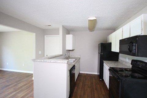 A kitchen with black appliances and white cabinets.