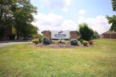 Large sign for Hazelton Apartments with plants around it