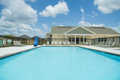 A large swimming pool in front of a building with a blue umbrella.