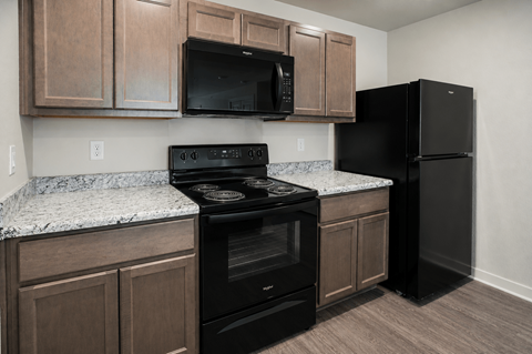 A kitchen with black appliances and brown cabinets.
