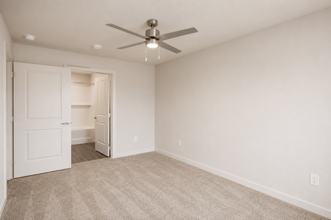 A room with a ceiling fan and carpeted floor.