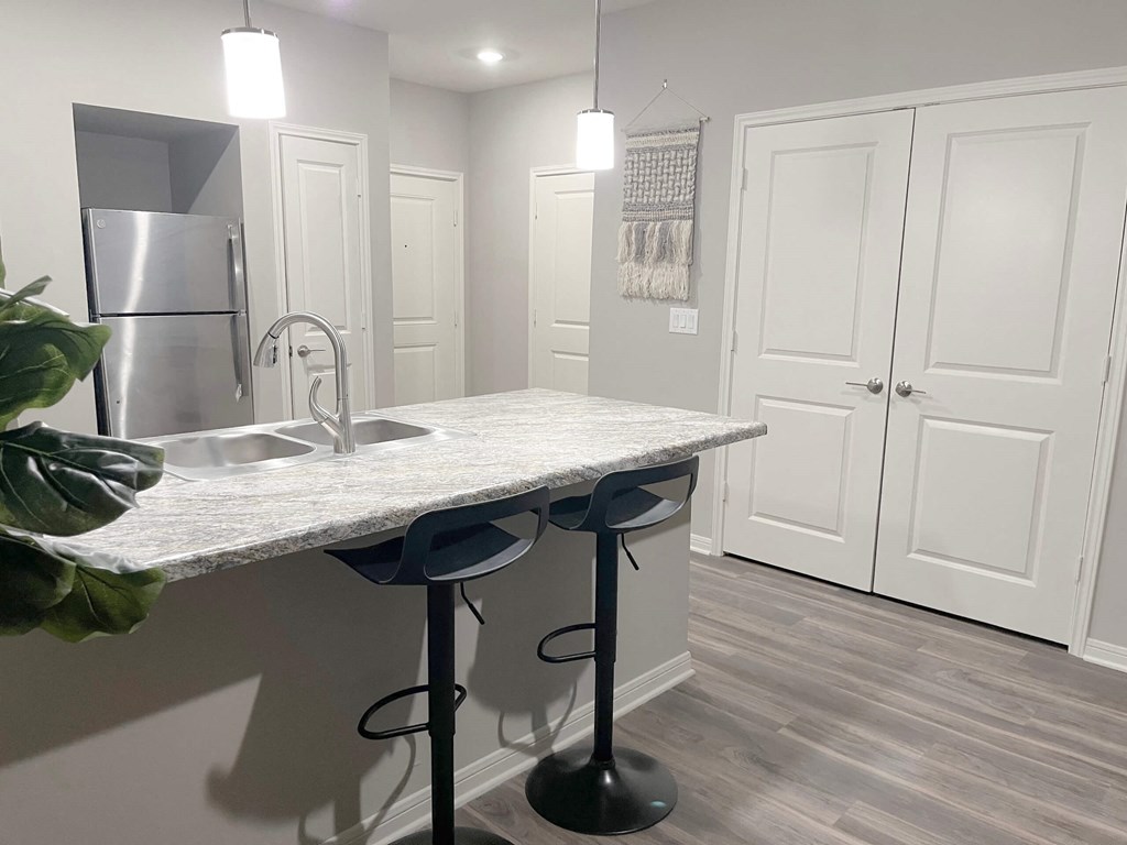 a kitchen with a marble counter top and a stainless steel refrigerator