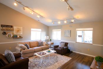 Clubhouse with brown couches and chairs and a white coffee table at CHA Logansport