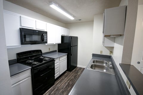 a kitchen with black appliances and white cabinets and a stainless steel sink
