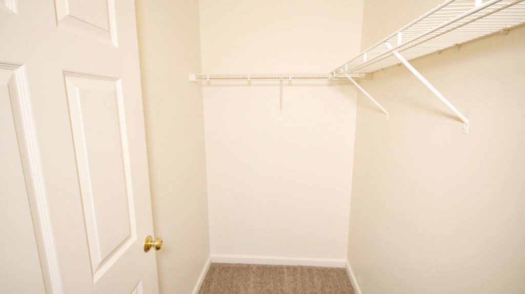 a walk in closet with a white closet door and a door to a closet