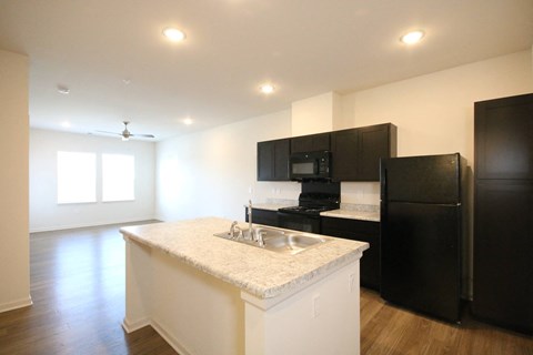 A kitchen with black cabinets and a white island.