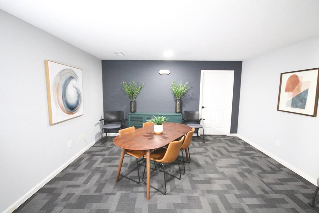 A conference room with a table, chairs, and two potted plants.