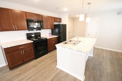 A kitchen with wooden cabinets and a black refrigerator.