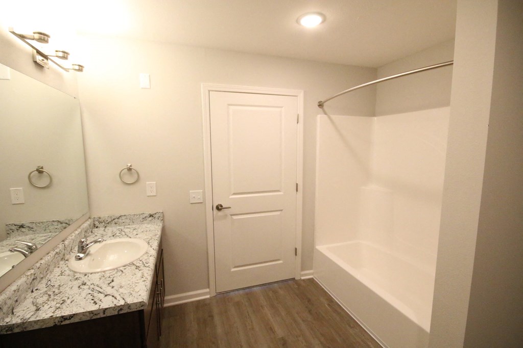A bathroom with a sink, mirror, and shower.