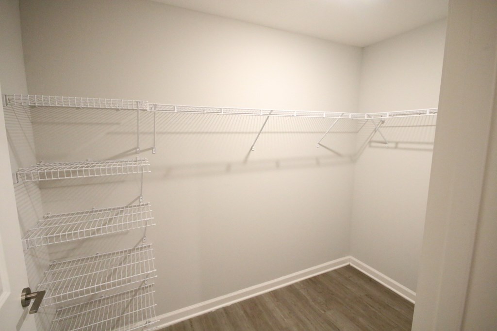 A white closet with a wooden floor and shelves.