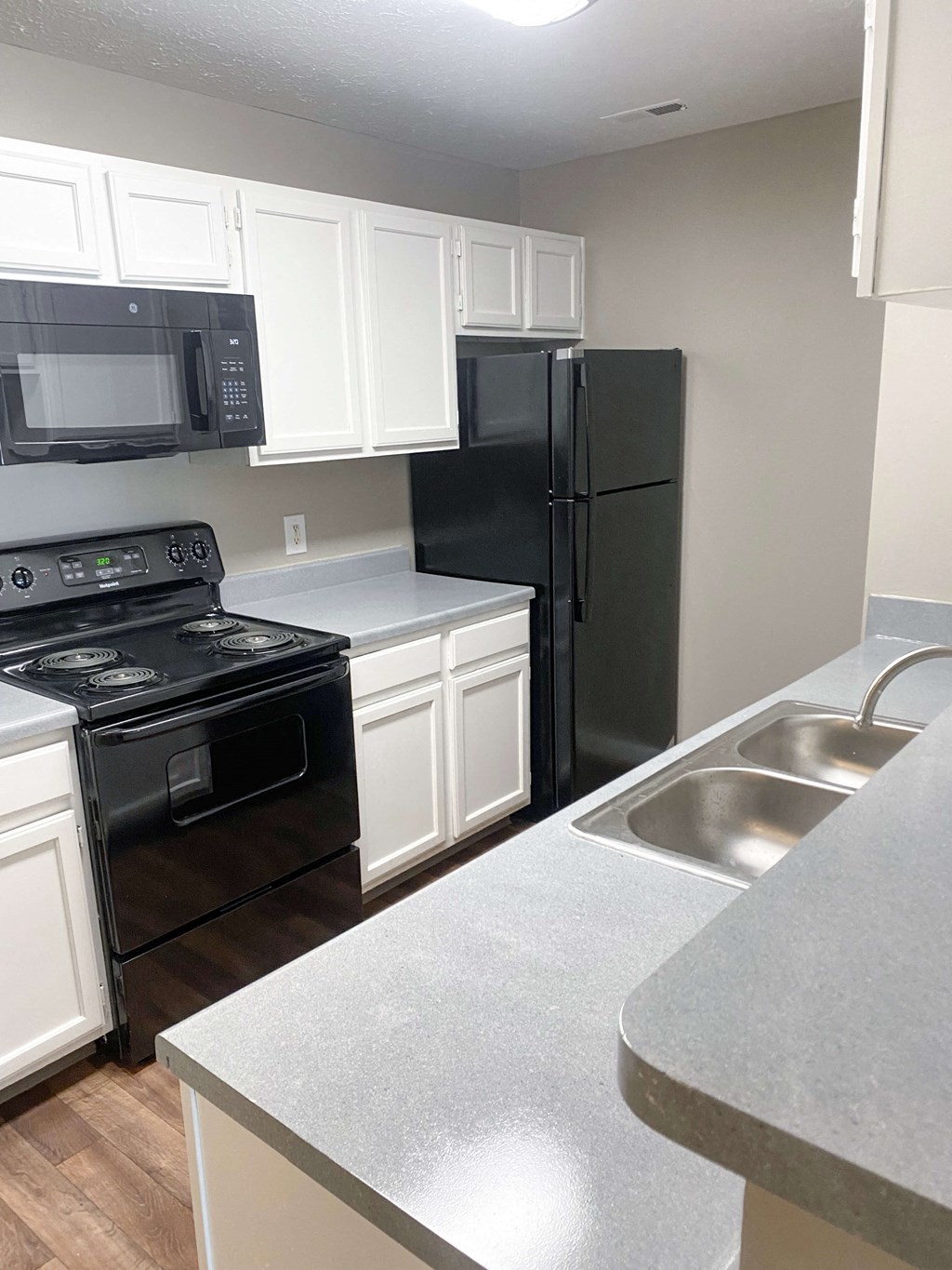 Kitchen with white cabinets and black appliances at Summerset Apartments