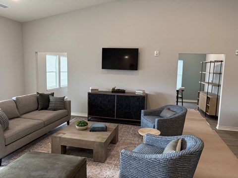 A living room with a grey sofa, a coffee table, and a television mounted on the wall.