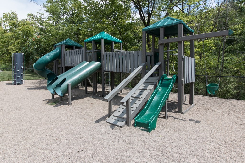 A playground with a green slide and a wooden structure.