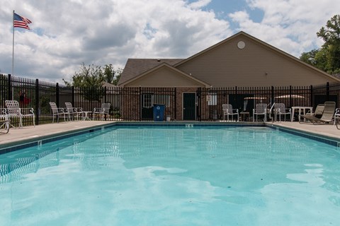A pool in front of a building with a flag on the left.