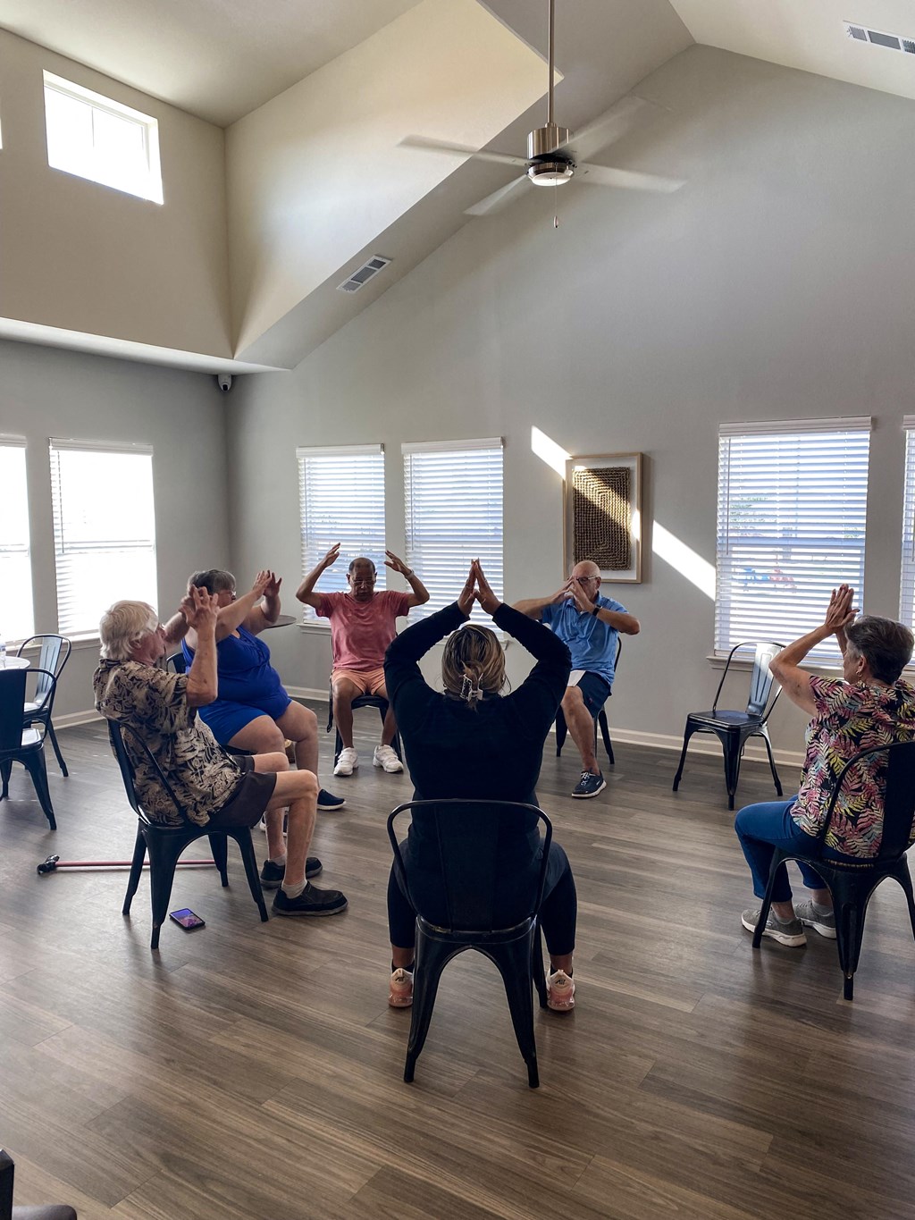 a group of people sitting in a circle in a class room with their hands up