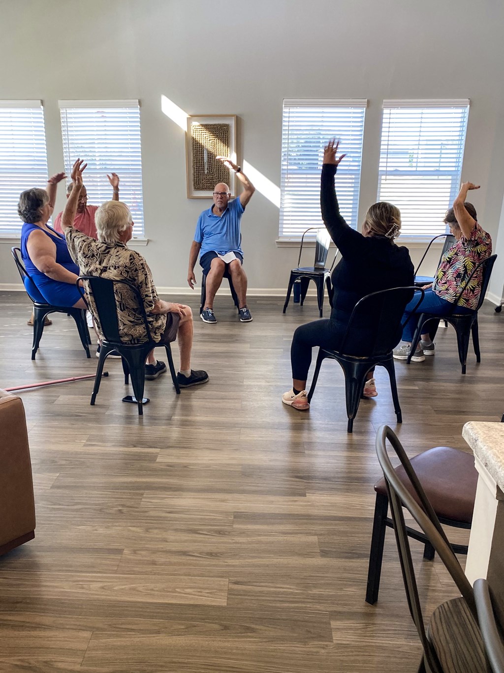 a group of people sitting in a circle with their hands up in a class room