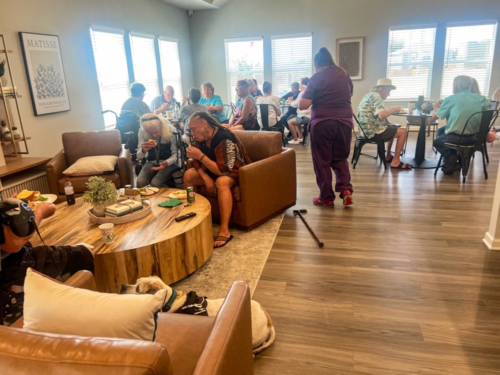 people sitting in a living room with couches and tables