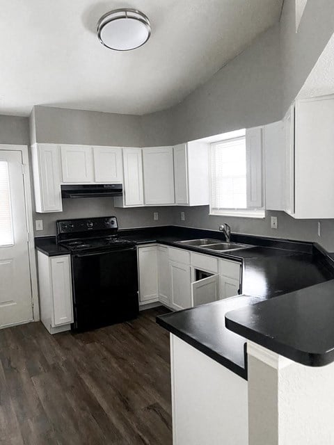 an empty kitchen with white cabinets and black counter tops