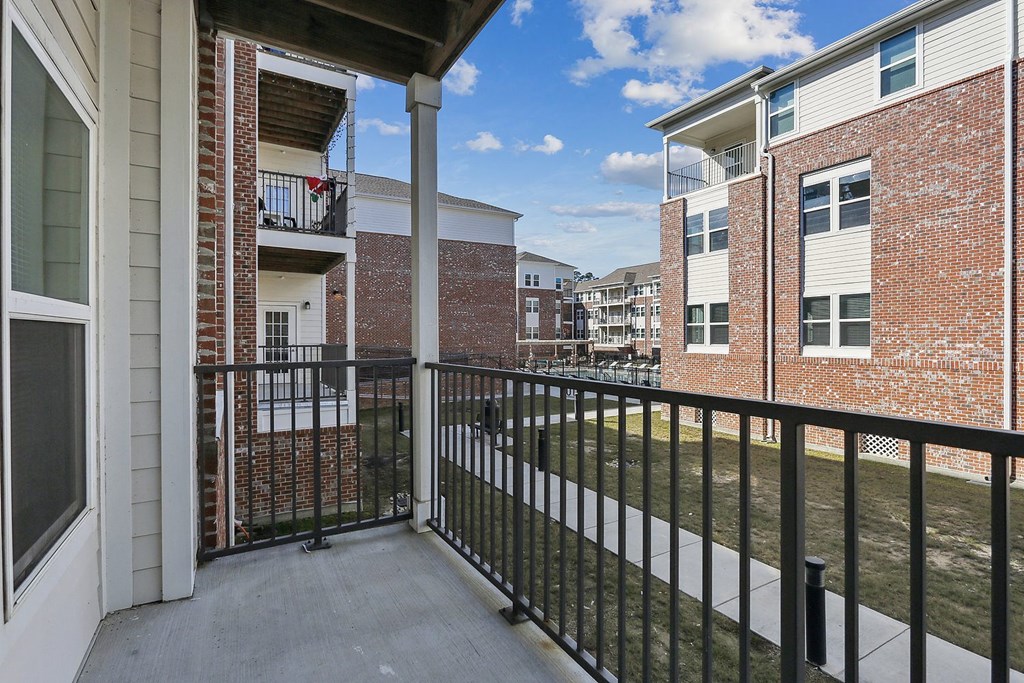 the spacious balcony has a view of a yard and apartments