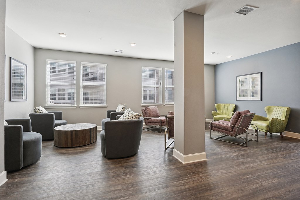 a community room with couches chairs and tables and windows at The Lofts apartments in Slidell, LA