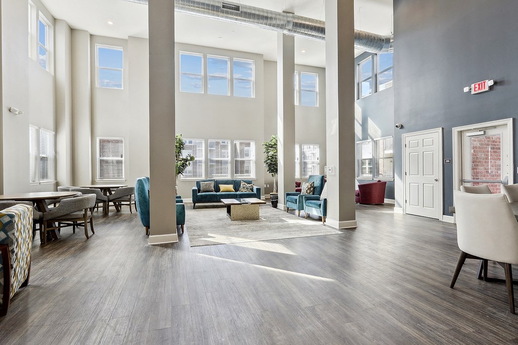 a lobby with couches chairs and tables and large windows at The Lofts in Slidell