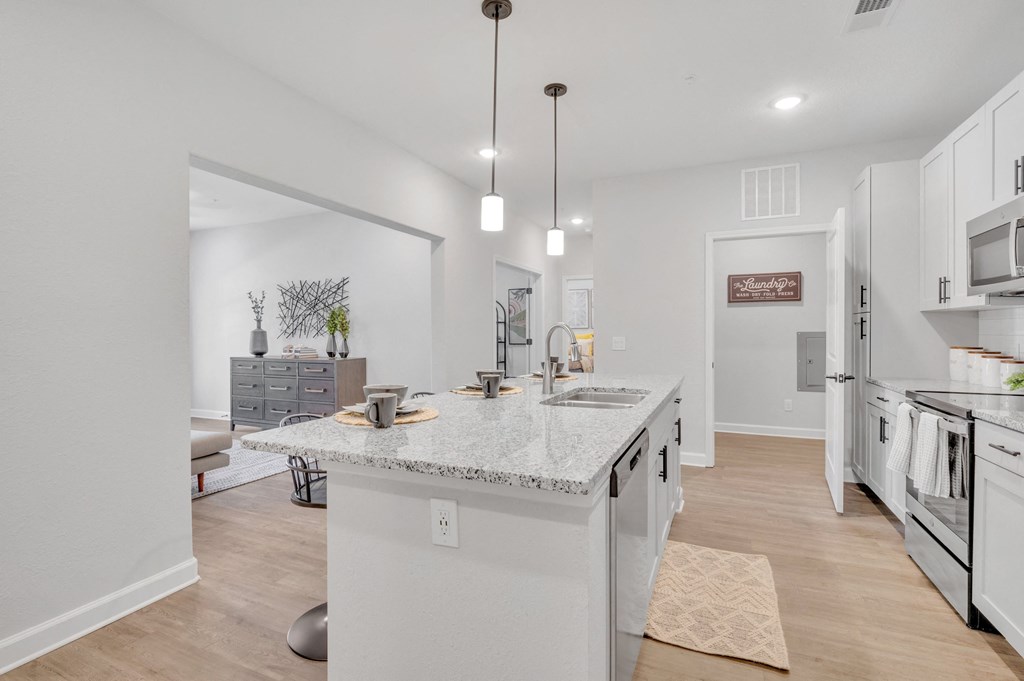 an open kitchen with a marble counter top and a large island at spire apartments