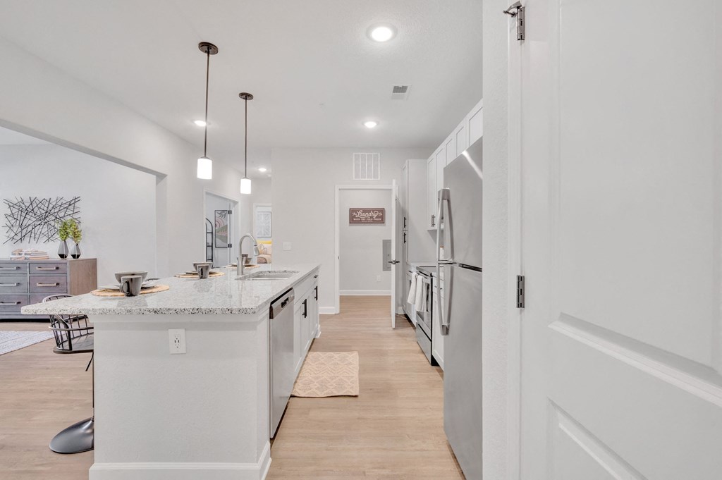 a white kitchen with a marble counter top and white appliances at spire apartments in charlotte nc