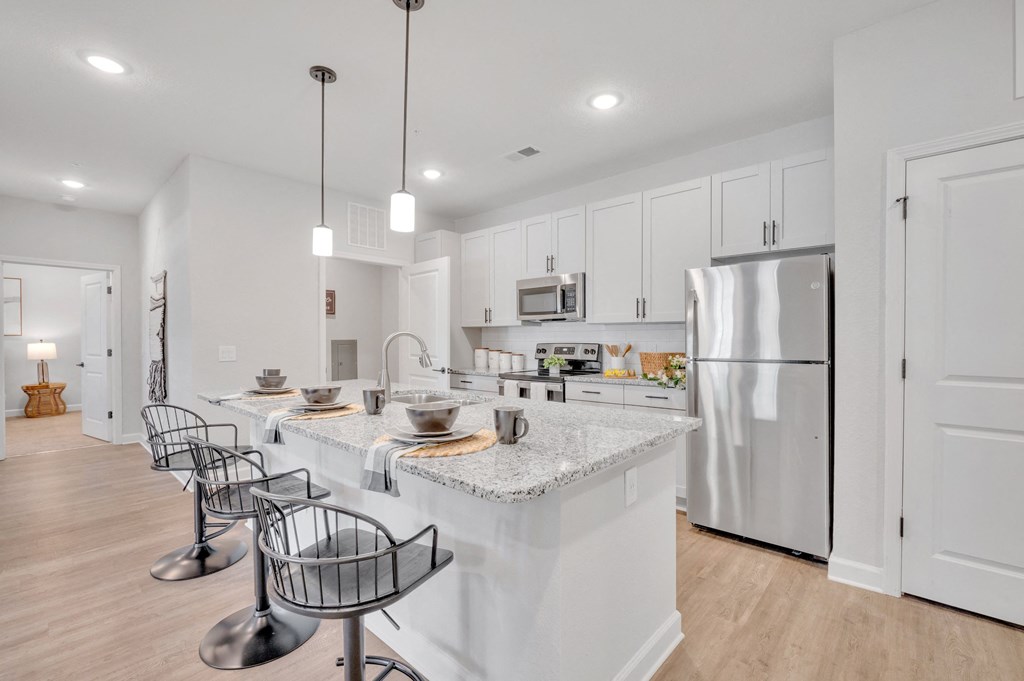 a large kitchen with an island with bar stools and a stainless steel refrigerator at spire luxury apartments in charlotte nc
