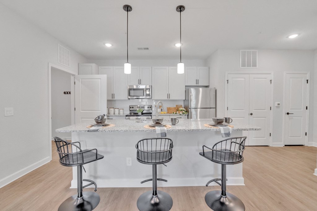 a kitchen with an island and bar stools in front of a kitchen counter top at spire apartments