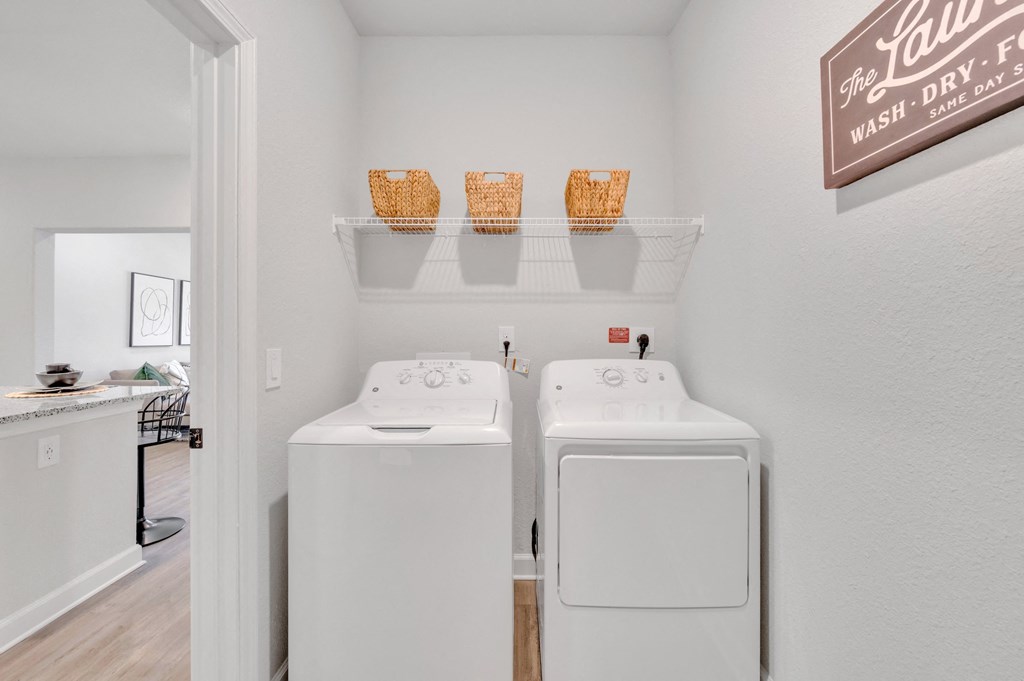 two washers and dryers in a laundry room with a door to a kitchen at spire apartments