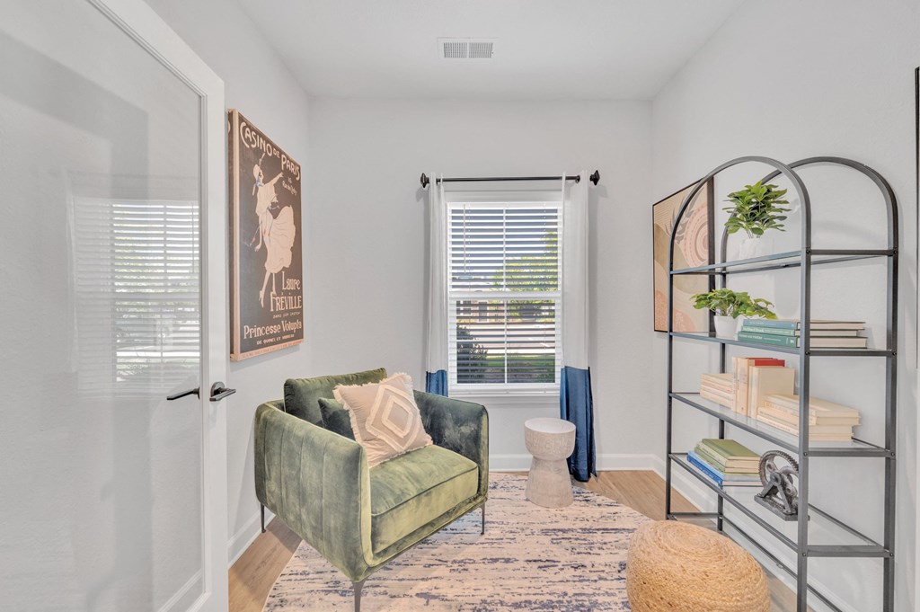 an office with a green chair and a bookshelf with a window at spire apartments in charlotte nc
