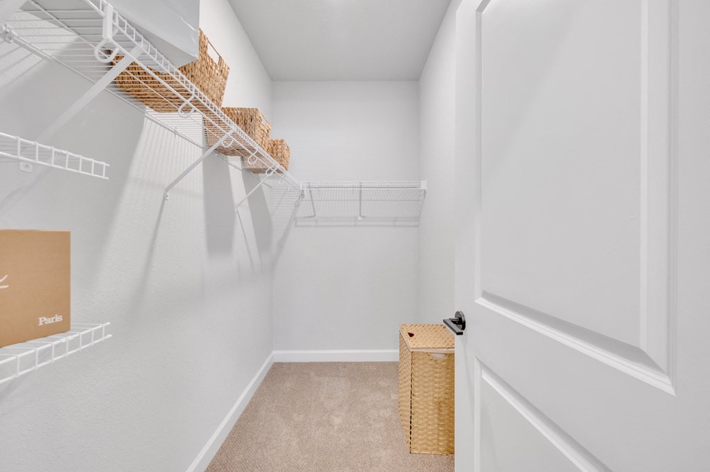 a walk in closet with white walls and shelves and a basket on the floor at spire luxury apartments in charlotte nc