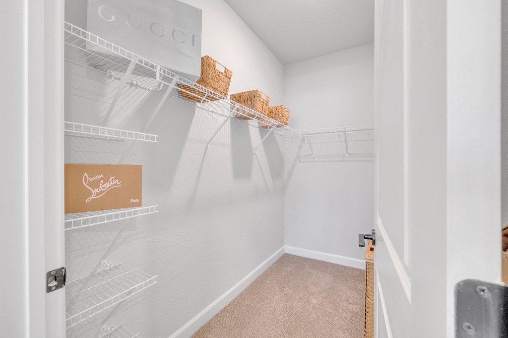 a walk in closet with white walls and shelves and a closet door open at spire apartments in charlotte nc