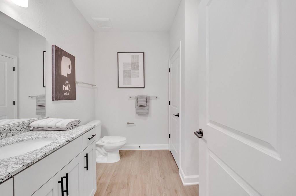 a bathroom with a toilet and a sink and a mirror at spire apartments in charlotte nc