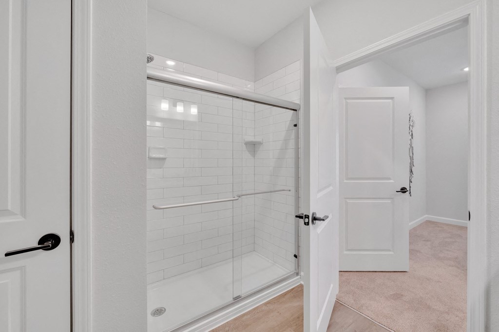 a white bathroom with a shower and a door at spire apartments in charlotte nc