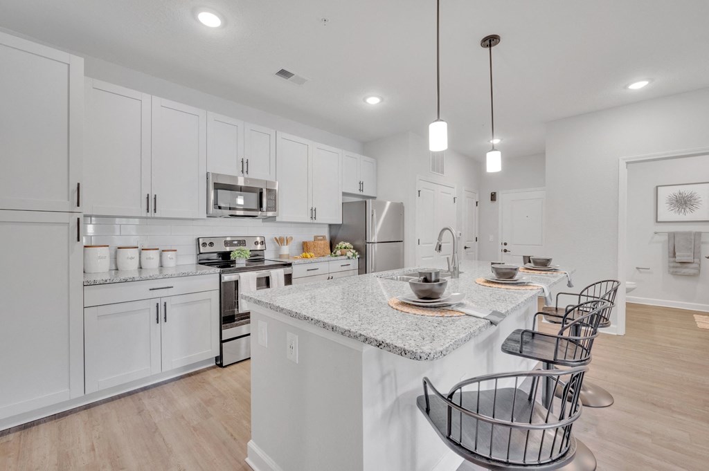 a large kitchen with white cabinets and a marble counter top at spire luxury apartments
