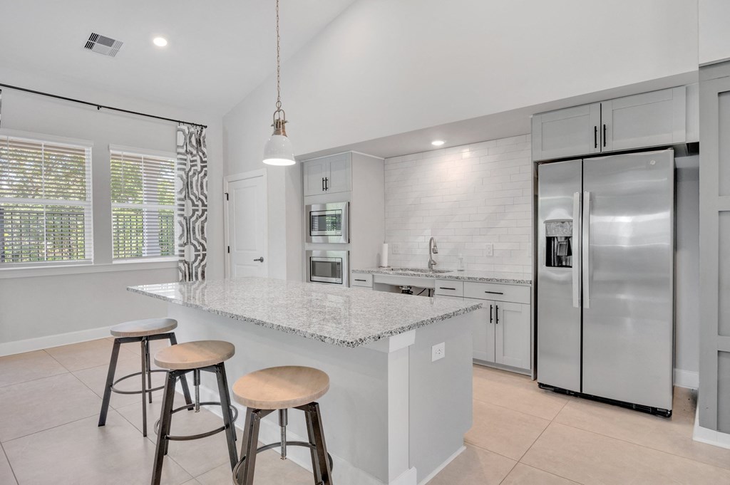 a kitchen with a large island with three stools at spire apartments