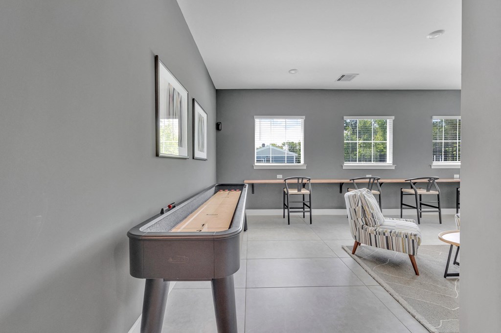 a game room with a shuffleboard table and a bar at spire apartments