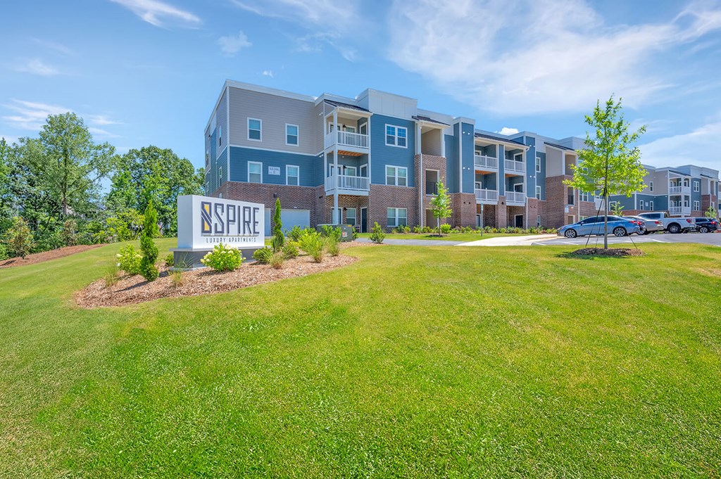 Exterior view of Spire apartment building with a lawn and a sign in front of it