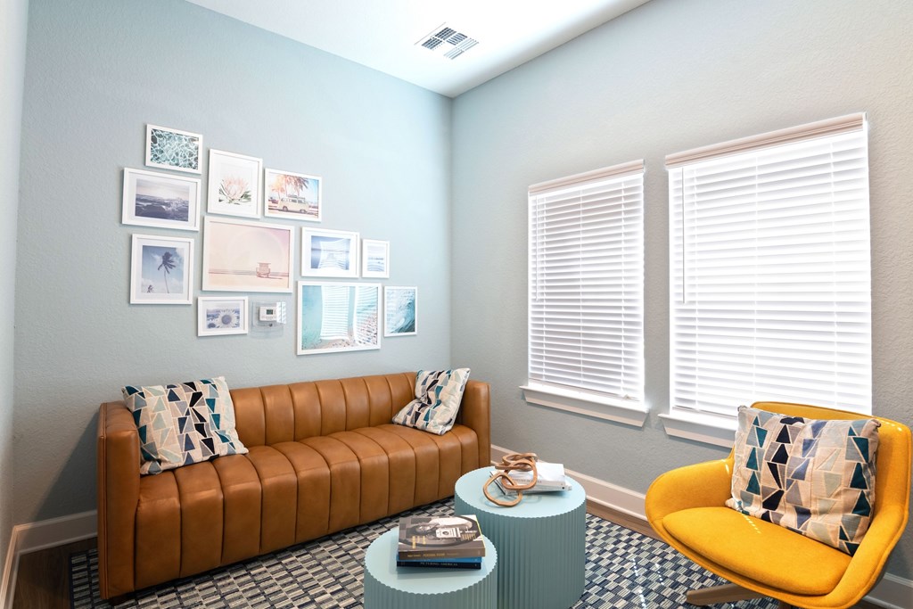 A living room with a brown couch, a yellow chair, and pictures on the wall.