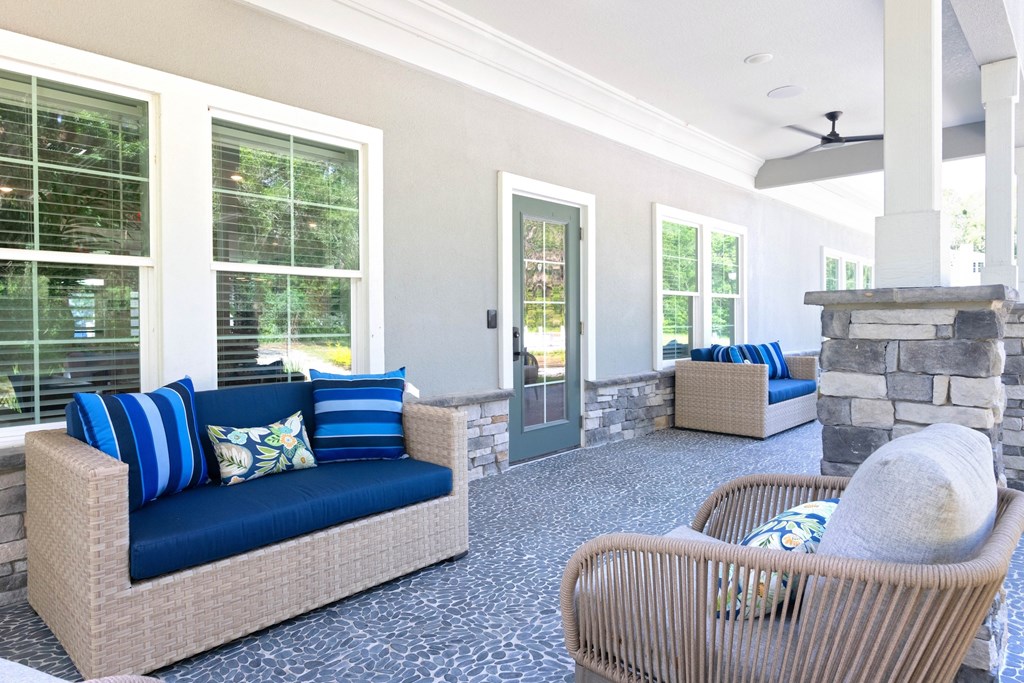 A patio with a couch, chair, and pillows.