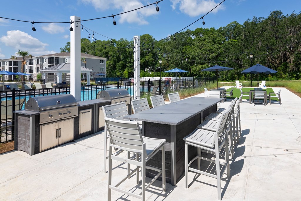A patio with a table and chairs overlooking a pool.