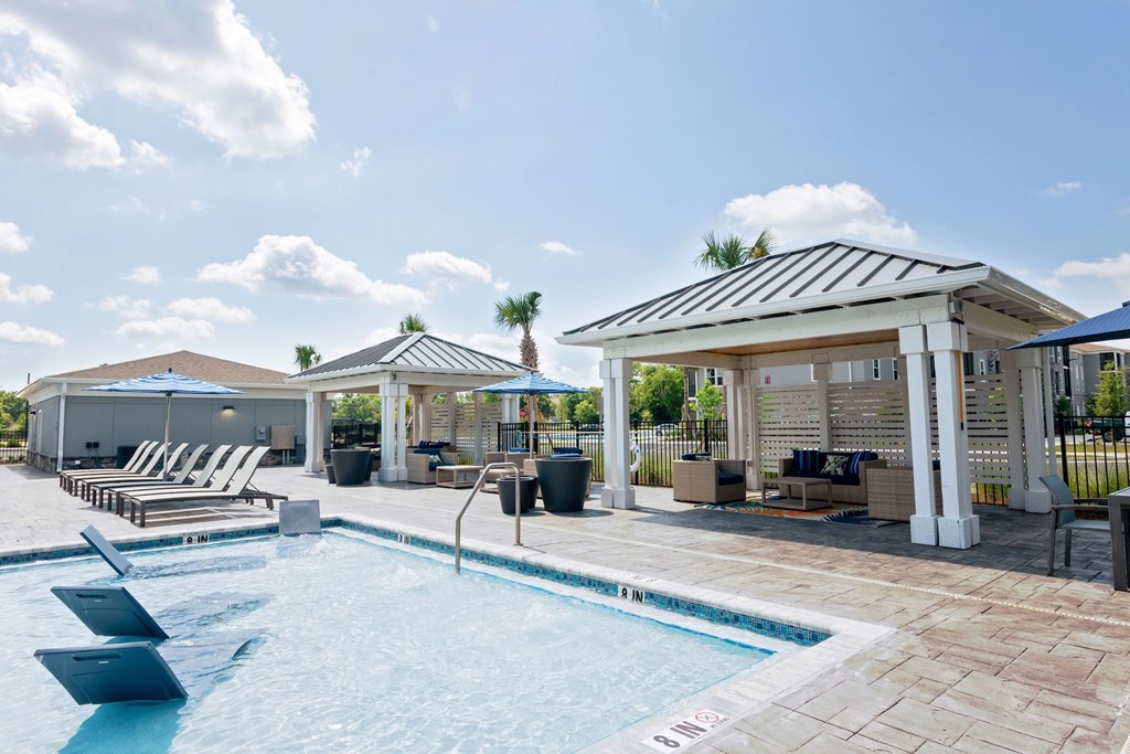 A pool with a sun lounger and a gazebo.