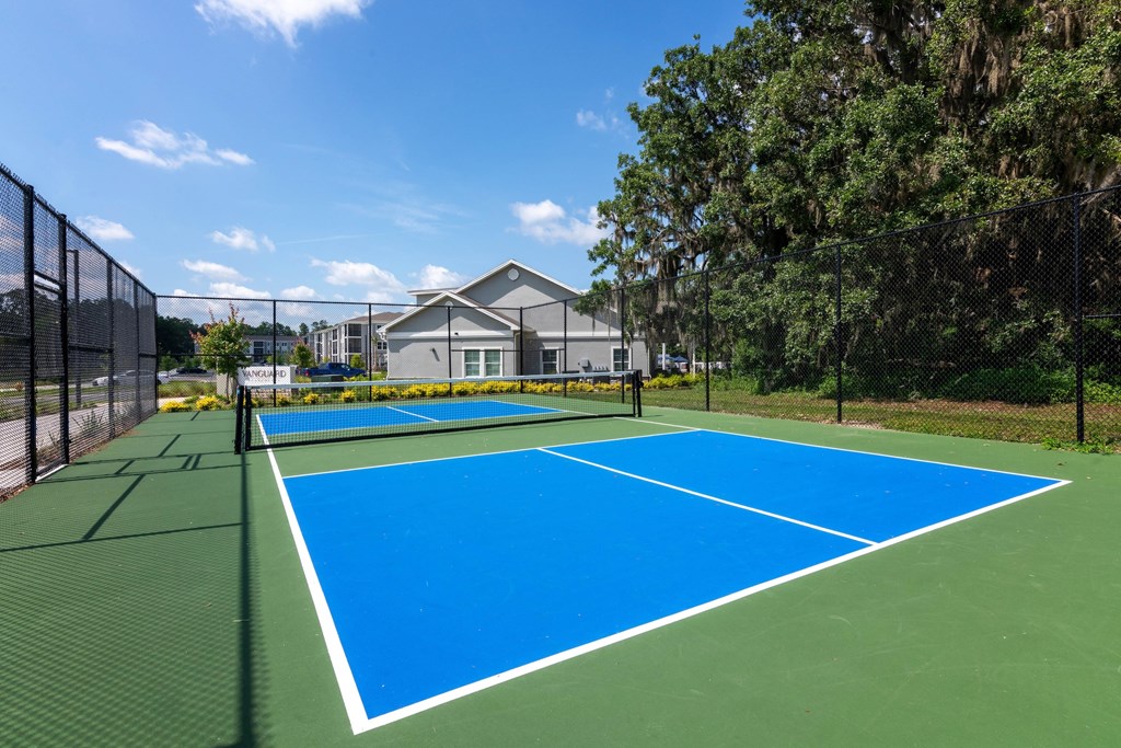 A tennis court with a green and blue surface surrounded by a fence.