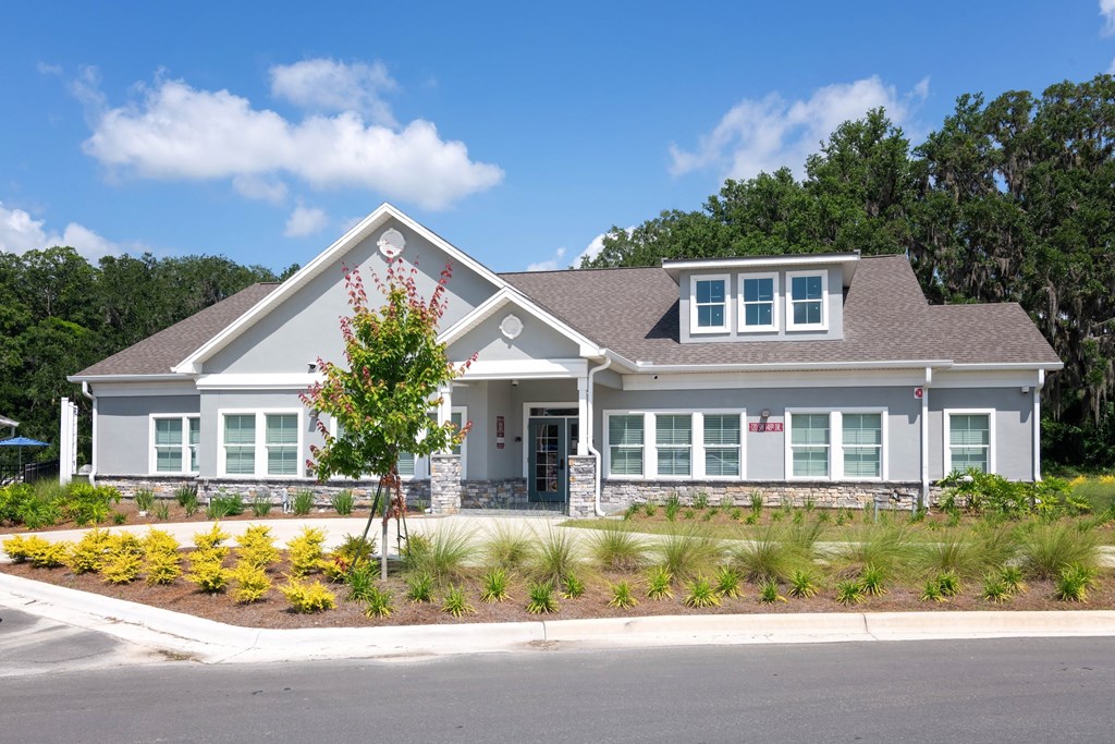 A house with a grey roof and white walls with a red flower on the front.