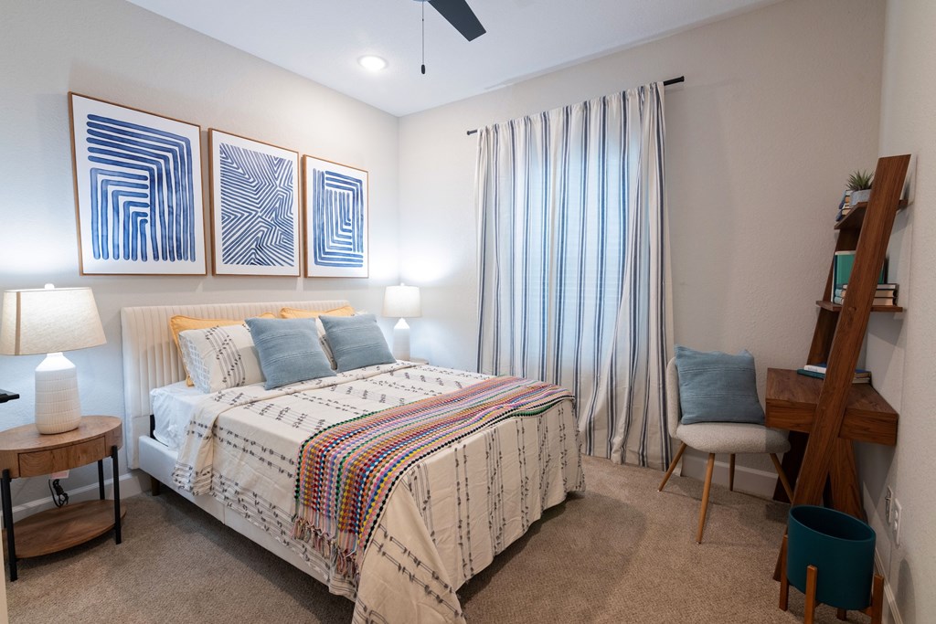 A bedroom with a bed, chair, and artwork on the wall.