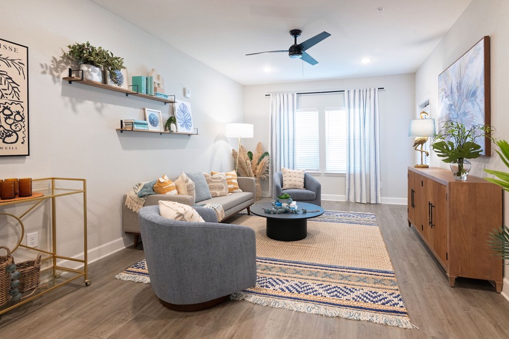 A living room with a grey sofa, a round coffee table, and a ceiling fan.