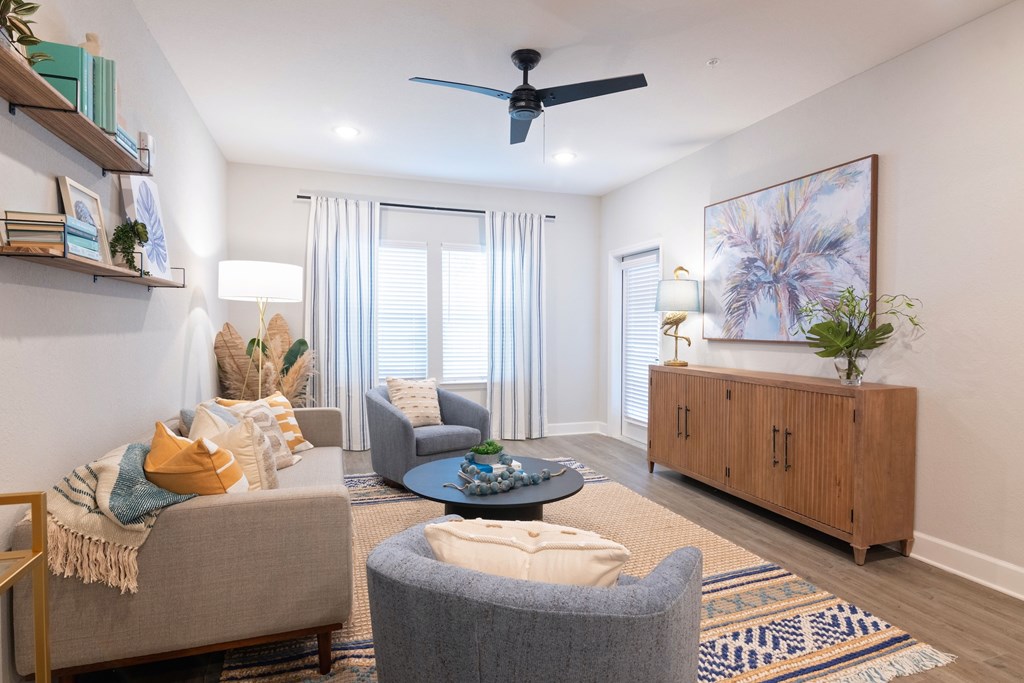 A living room with a grey couch, a blue round table, and a wooden cabinet.