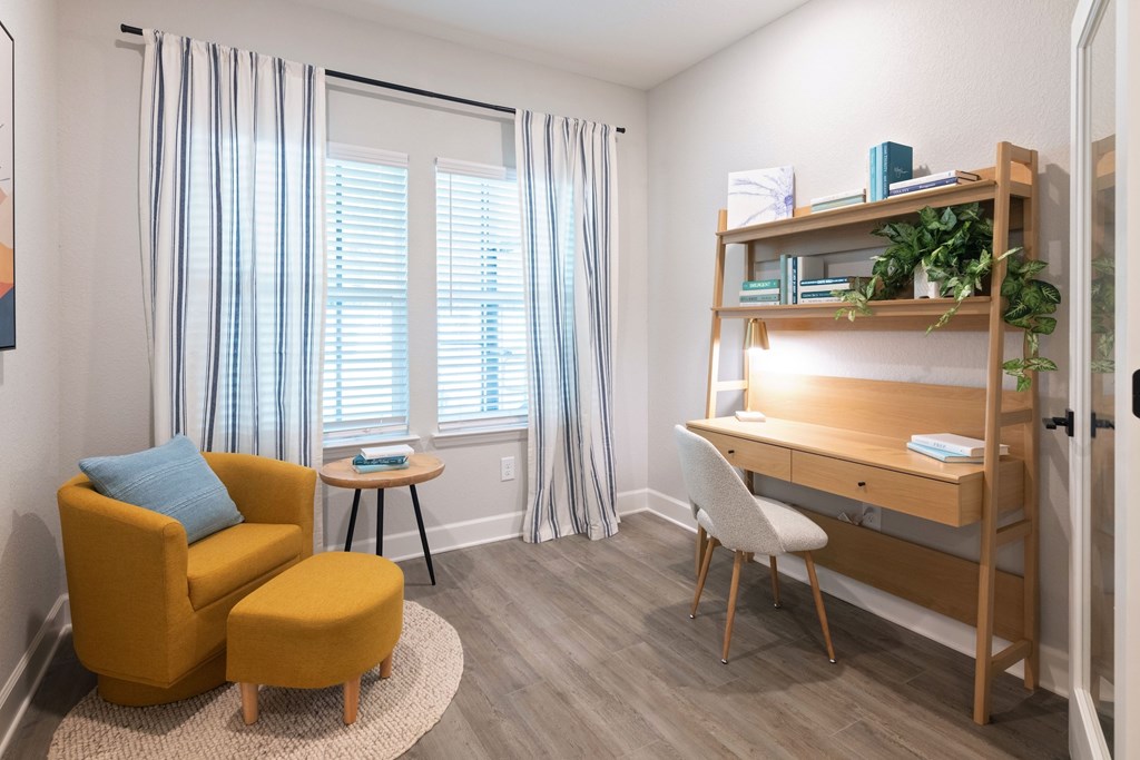 A room with a yellow chair and a wooden desk.