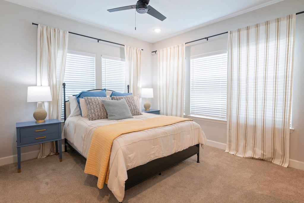 A bedroom with a bed, nightstand, and window with curtains.